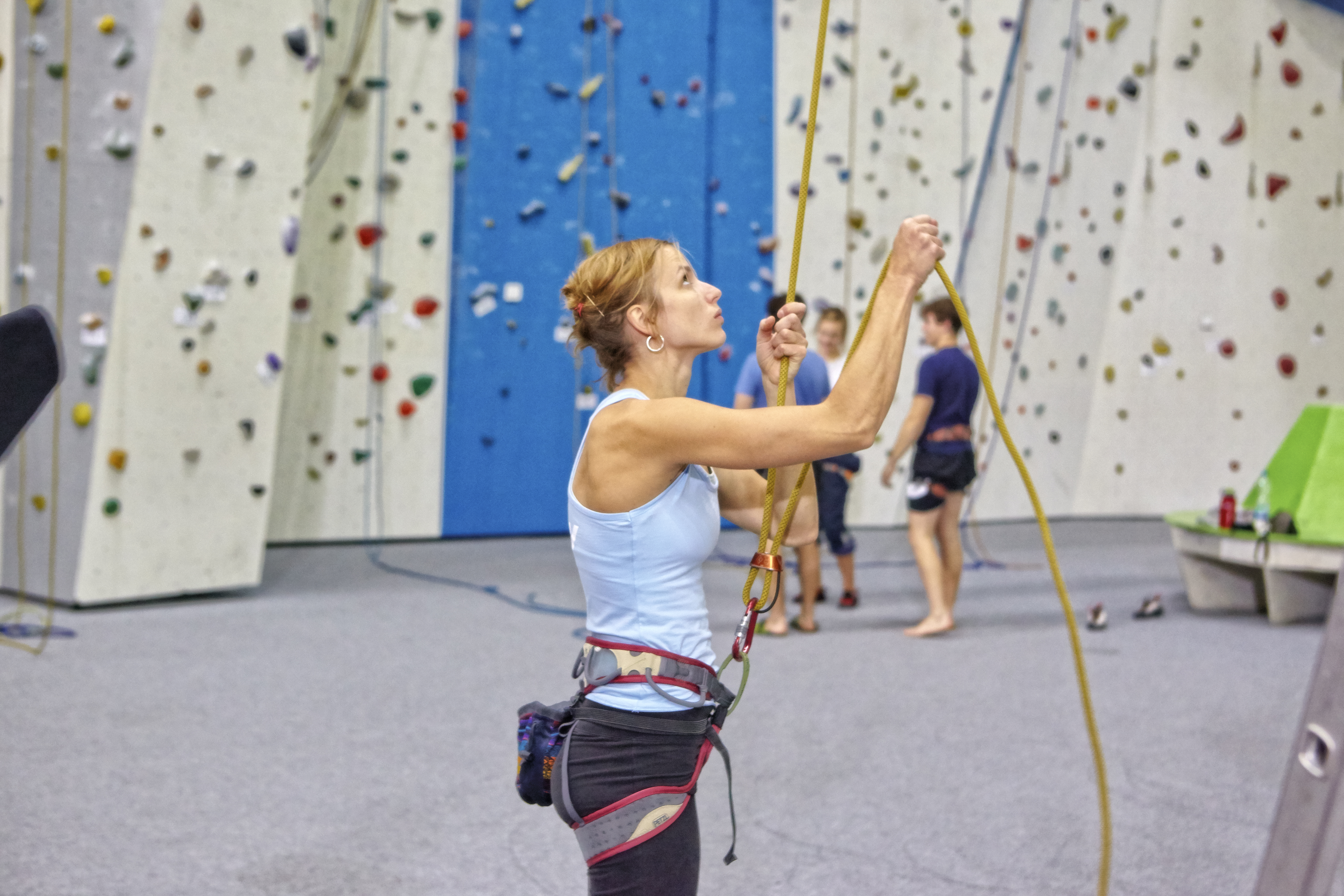 Frau sichert in der Kletterhalle jemanden. Sie trägt einen Klettergurt. Fotograf: Jörg Saibou, Köln.