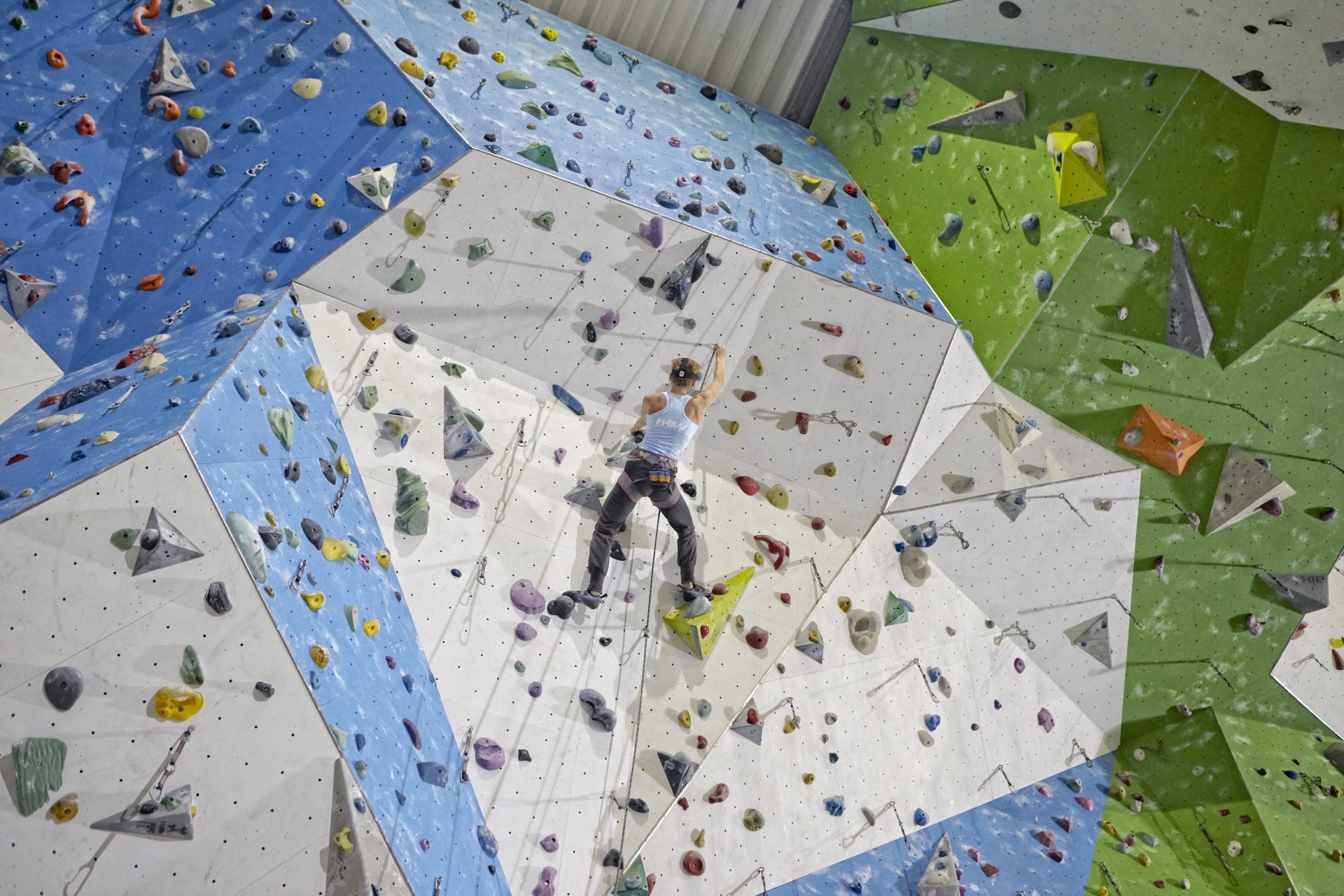 Frau klettert in einer Kletterhalle an einer Wand. Fotograf: Jörg Saibou, Köln.